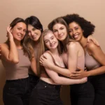 cinco-mulheres-africanas-e-caucasianas-bonitas-em-jeans-pretos-de-tops-marrons-olham-para-a-camera-em-fundo-bege_197531-31847